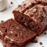 A freshly sliced, golden-brown Banana Bread infused with rich chocolate and bold espresso, garnished with cocoa powder and banana slices.